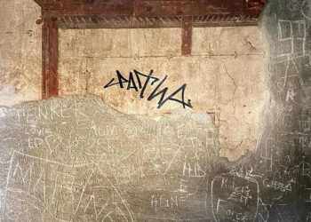 Turista firma con marcador permanente en la pared de una antigua ciudad romana